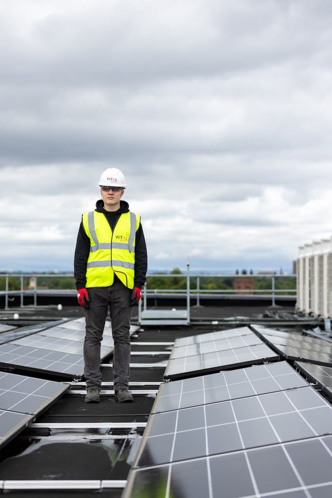 Worker Standing Among Solar Panels on Rooftop